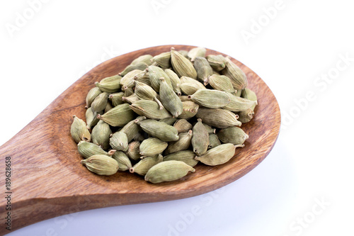 whole cardamom seeds  on wooden spoon isolated on white background