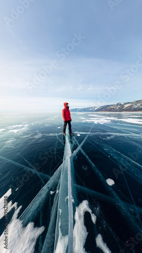 Panorama man stand on cracks on blue ice of Lake Baikal from Olkhon