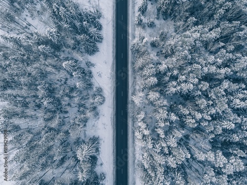 Country road going through the beautiful snow covered landscapes. Aerial view.