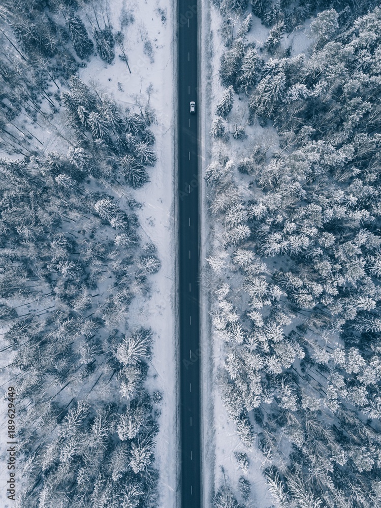 Obraz premium Country road going through the beautiful snow covered landscapes. Aerial view.