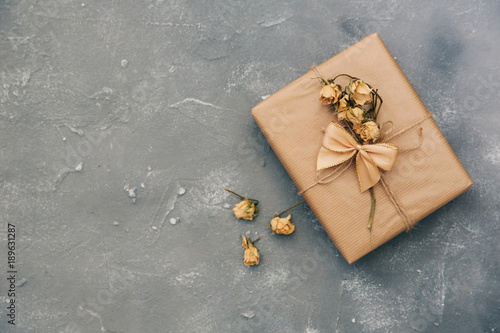 Wrapped brown present box with dry flowers on vintage background photo