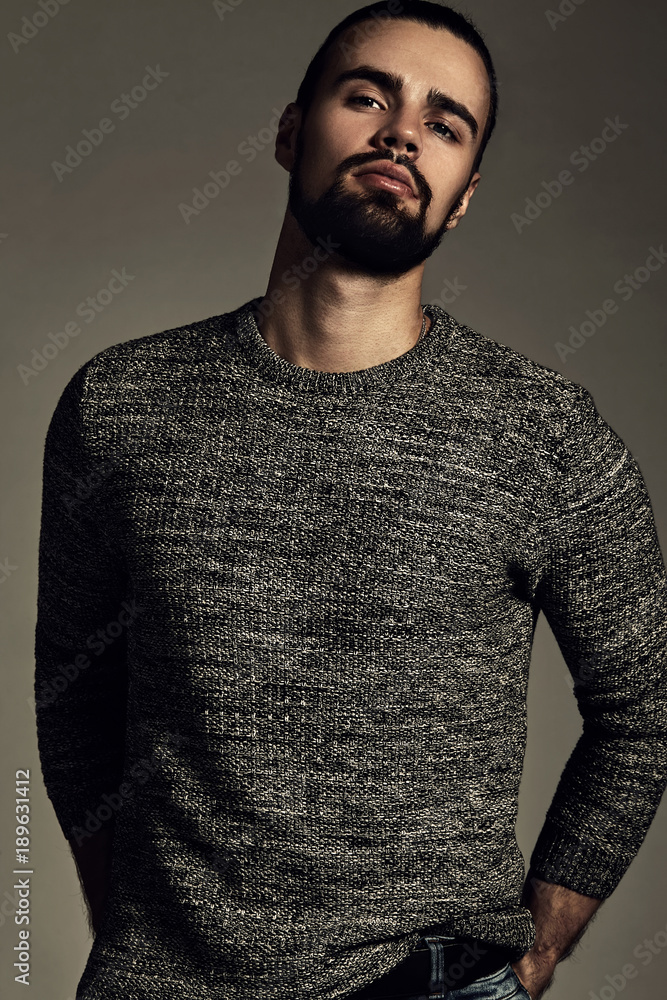 Fototapeta premium portrait of handsome fashion stylish hipster lumbersexual model dressed in warm sweater posing in studio. Metrosexual