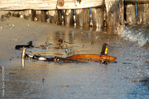 wreck of a rusty bicycle lays in the waterline of a frozen sea. photo