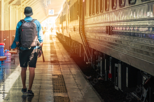 Man with backpack walking on the plateform in a train station