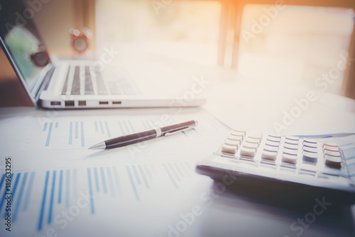 Laptop with financial documents on wooden table