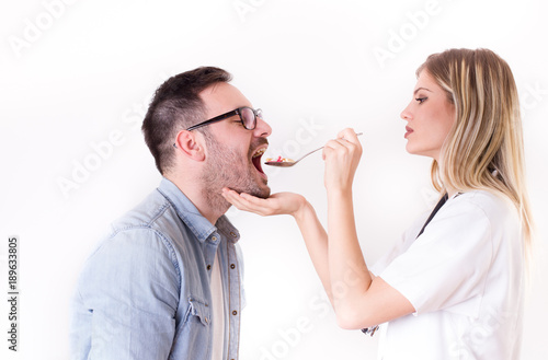 Female doctor giving spoon with pills to patient