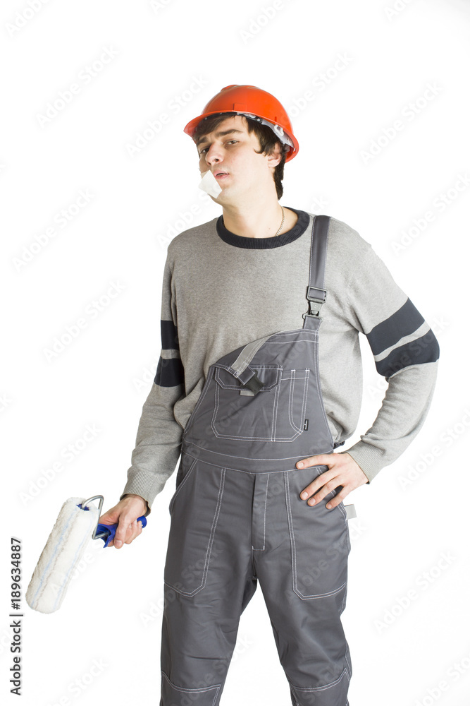 A young man in working grey clothes and orange hard helmet man with tape over mouth. Isolated on white background. A young man in working grey clothes and orange hard helmet man with tape over mouth. Isolated on white background.