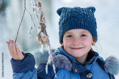 winter, happy smiling girl holding a frozen branch of a tree