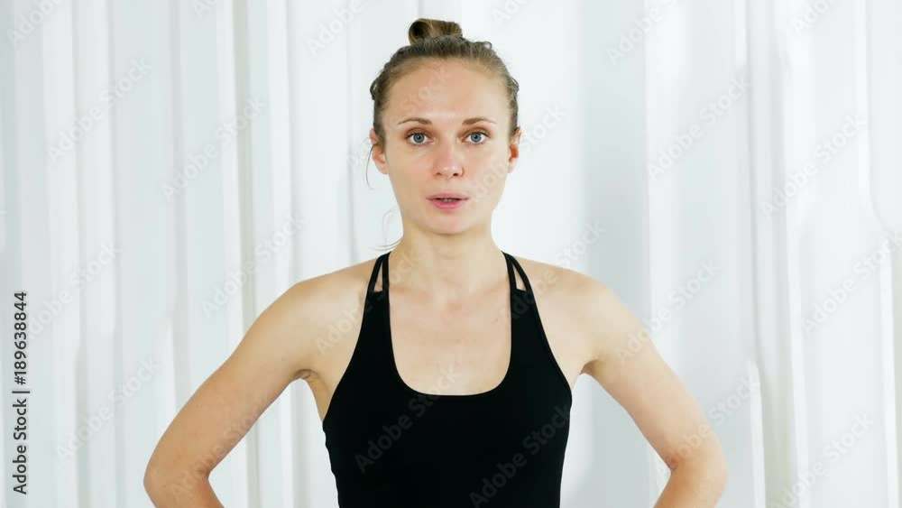 yoga girl in black dress is standing in a white studio and breathes deeply yoga girl in black dress is standing in a white studio and breathes deeply