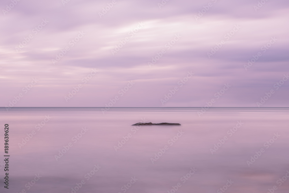 Obraz premium Sea open space and rocks in the water. Long exposure. Artistic photo, minimalism, simplicity and gentle lilac tones. 