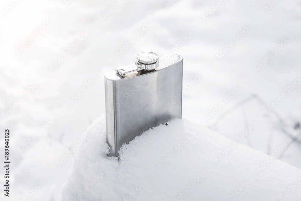 Metal flask for alcohol on snow in the woods. Tourism, outdoor recreation. Metal flask for alcohol on snow in the woods. Tourism, outdoor recreation.