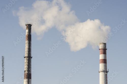 A coal-fired plant produces smoke into the sky, thereby sucking up the earth's atmosphere. Smoke from a chimney against a blue sky