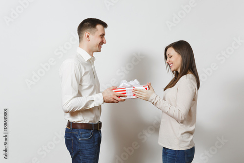 Cute couple in love. Man giving woman present box with gift isolated on white background. Copy space for advertisement. St. Valentine's Day, International Women's Day, birthday, holiday concept.