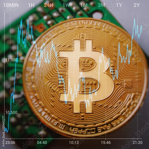 Golden Bitcoin Cryptocurrency on a computer board. Against the background is a graph of the price change Bitcoin. Macro photo