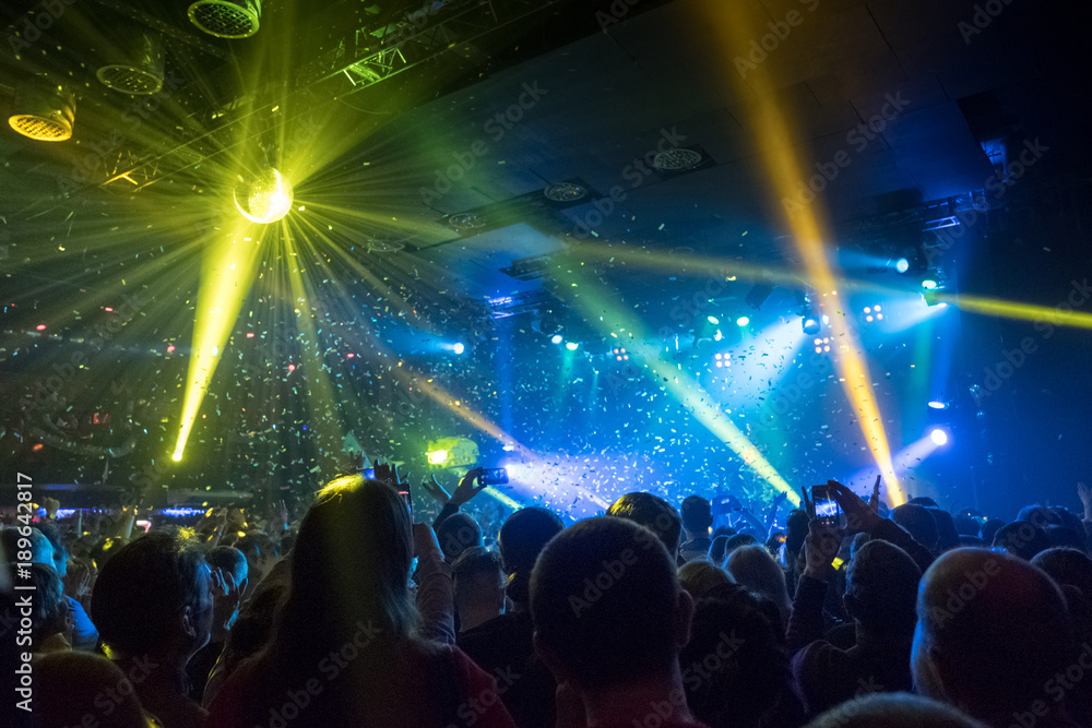 shiny confetti during concert and crowd of spectators with their hands up