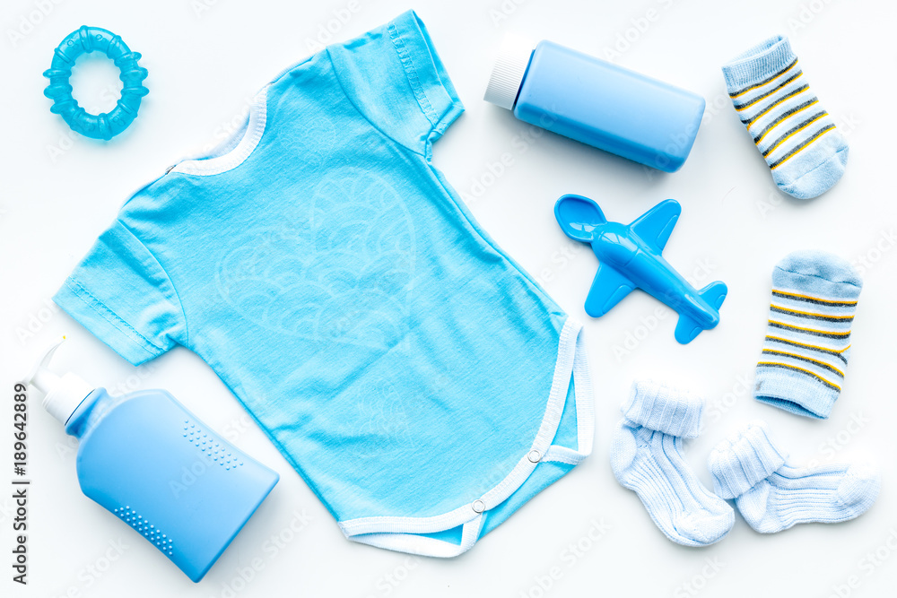 Blue set for newborn boy. Baby bodysuit, socks, airplan toy, soap and powder on white background top view Blue set for newborn boy. Baby bodysuit, socks, airplan toy, soap and powder on white background top view