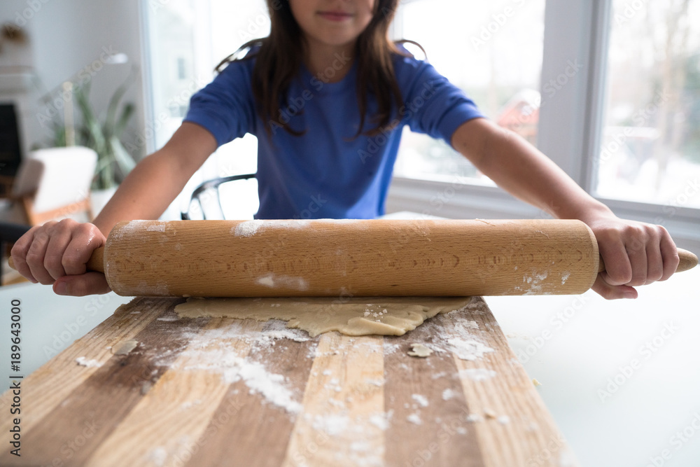 Young girl rolling out pastry with rolling pin. Young girl rolling out pastry with rolling pin.