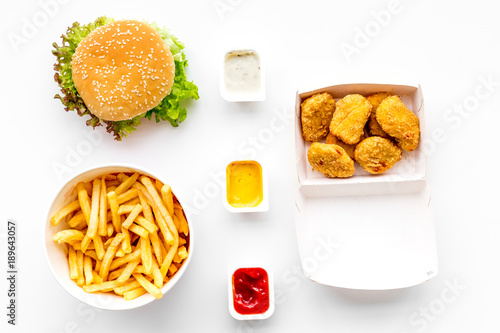 Fast food. Chiken nuggets, burgers and french fries on white background top view © 9dreamstudio