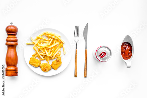 Fast food reastaurant. Chiken nuggets and french fries on plate on white background top view