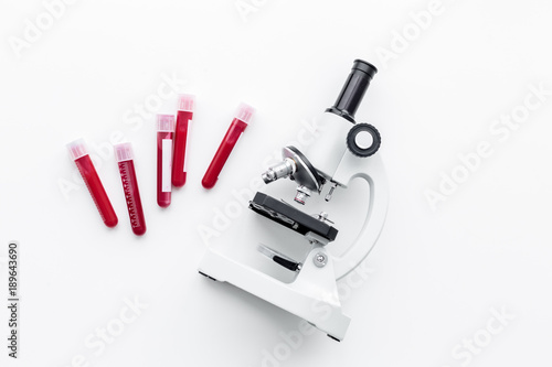 Blood analysis in clinacal lab. Test tubes near microscope on white background top view copy space