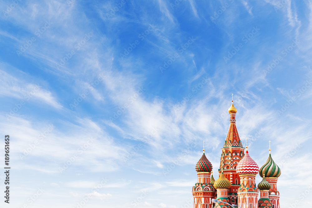 Domes of Saint Basil Cathedral on blue sky background. Famous landmark of Moscow, Russia. Bright sunny day with clouds. Cloudscape on blue sky. Place for text. - obrazy, fototapety, plakaty 