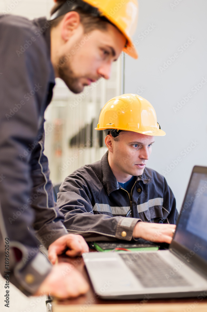 Field service engineers inspect relay protection system with laptop computer Field service engineers inspect relay protection system with laptop computer