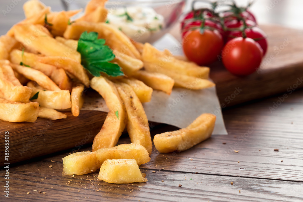French fries, cherry tomatoes, garlic sauce on a wooden brown background, close-up. Fast food. French fries, cherry tomatoes, garlic sauce on a wooden brown background, close-up. Fast food.