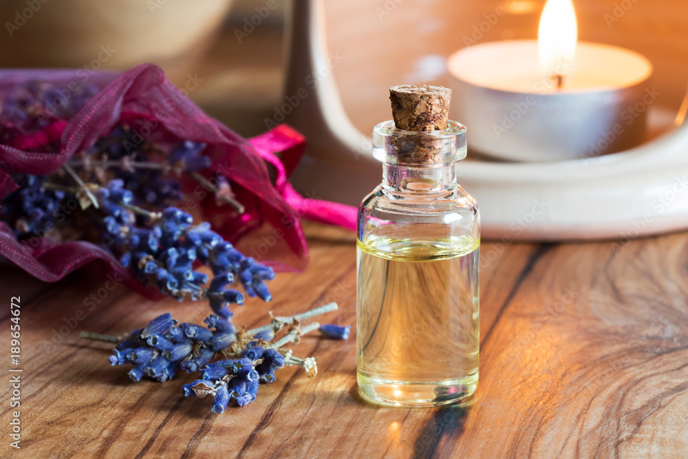 A bottle of lavender essential oil with dried lavender twigs A bottle of lavender essential oil with dried lavender twigs