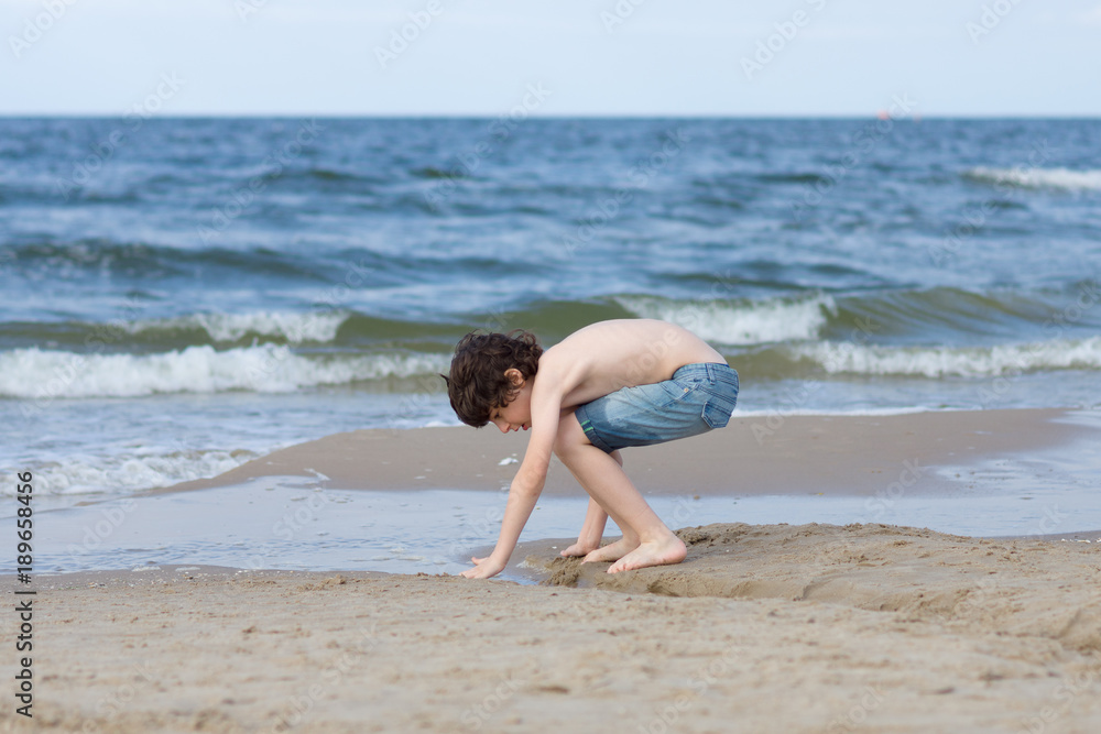 A guy in denim shorts is happy on the sandy beach of the sea. A guy in denim shorts is happy on the sandy beach of the sea.