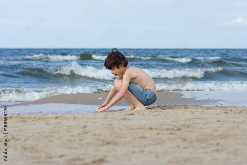 A guy in denim shorts is happy on the sandy beach of the sea. A guy in denim shorts is happy on the sandy beach of the sea.