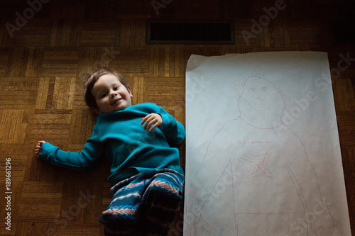 Foto Young boy laying by his traced likeness