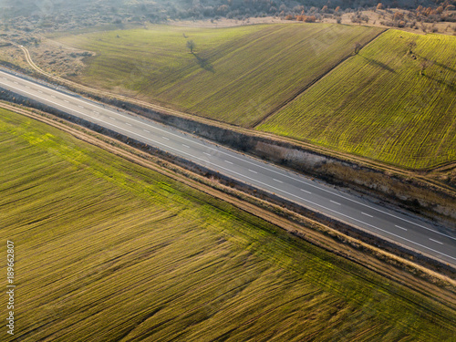 Aerial view of colorful wide field with sunshade . drone view of a firld in rural area with sunlight with a diagonal road