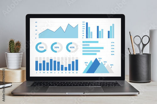 Graphs and charts elements on laptop screen on modern desk. All screen content is designed by me. Front view.