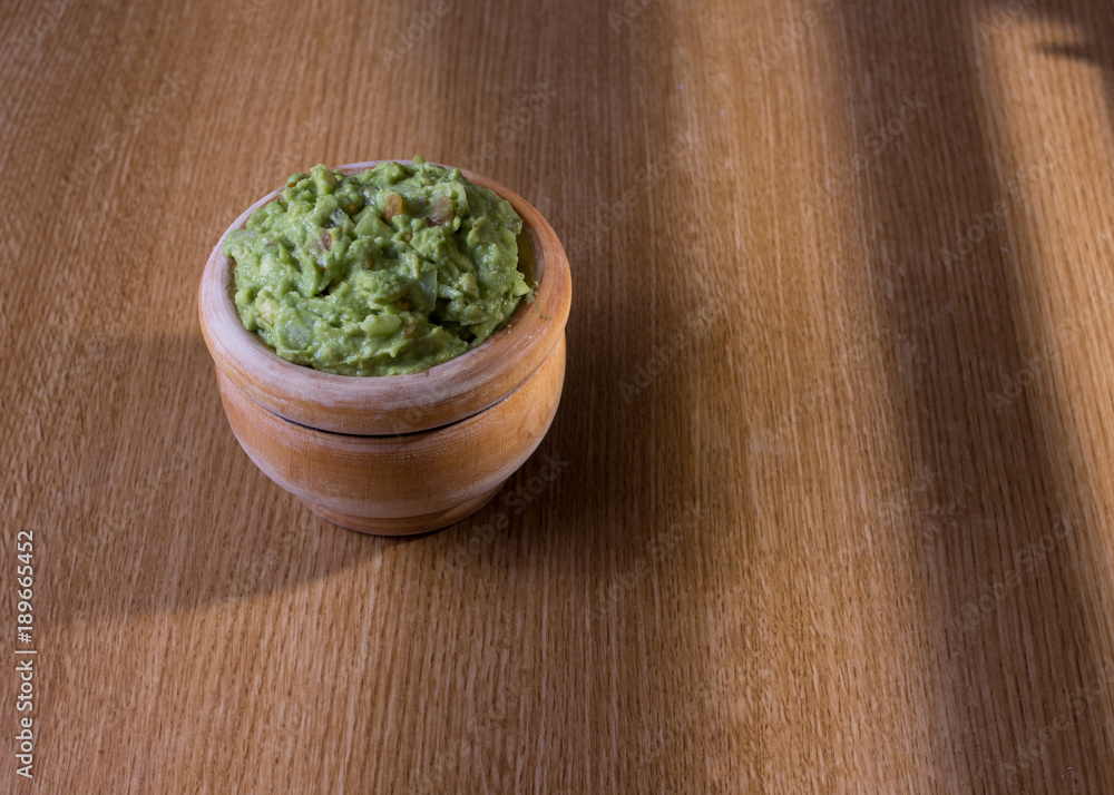 bowl of guacamole isolated on rustic table bowl of guacamole isolated on rustic table