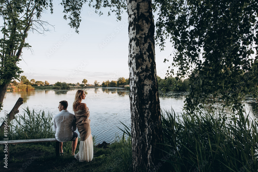 Very atmospheric photo on which a loving couple near a lake enjoys the sunset outside the city Very atmospheric photo on which a loving couple near a lake enjoys the sunset outside the city