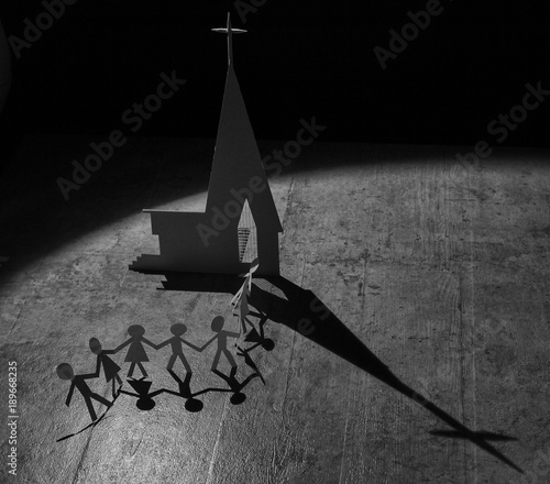Paper figures of people going to a church with shadow from spotlight
