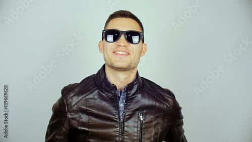 A young man wearing black glasses and a black jacket. H