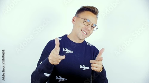 A young man in a blue sweater and glasses at a photo shoot.
