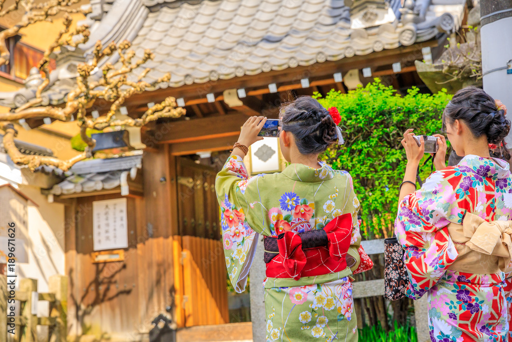 Japanese women in kimono take picture of Yasaka Shrine also known as Gion Shrine, one of the most famous shrines in Kyoto, Japan, between Gion District and Higashiyama District. Springtime.