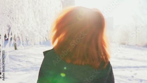 Young woman goes, turns to the camera and smiling, sunny winter day