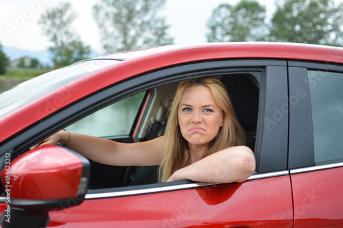 Young blonde girl in red car mocking at somebody