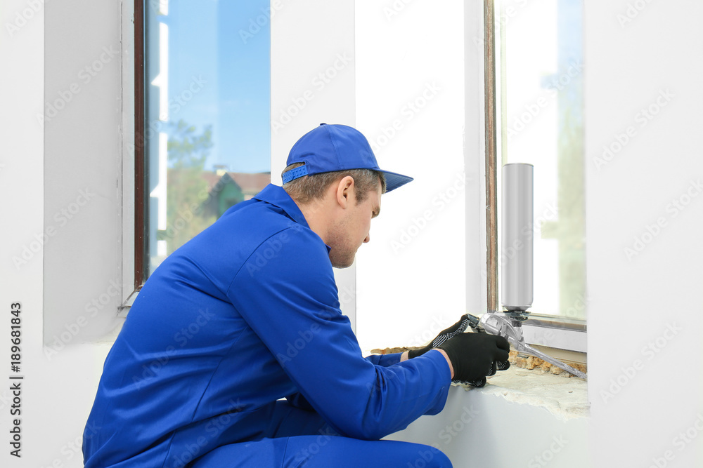 Construction worker repairing window in house Construction worker repairing window in house