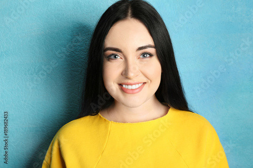 Portrait of young beautiful woman smiling against color background