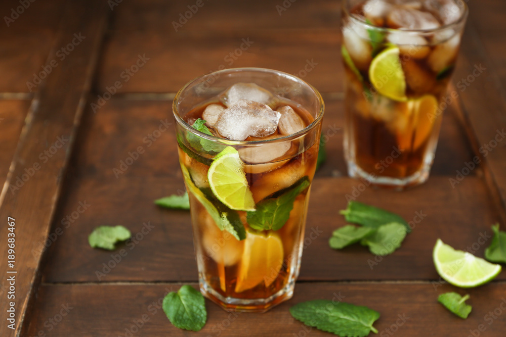 Glasses with Cuba Libre cocktail on wooden table Glasses with Cuba Libre cocktail on wooden table
