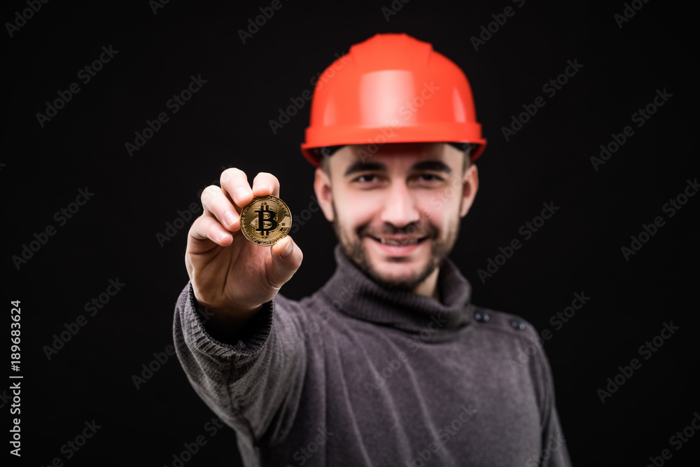 Handsome man miner in protective hemlet pointed bitcoin isolated on black background Handsome man miner in protective hemlet pointed bitcoin isolated on black background