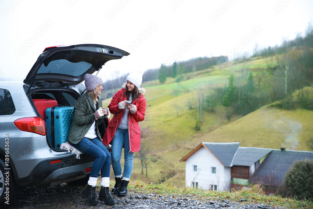 Obraz premium Female tourists near car in countryside