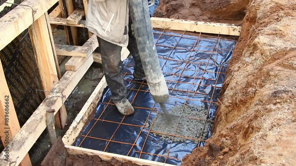 Pouring concrete into a newly built wooden house. Pouring concrete mix ...