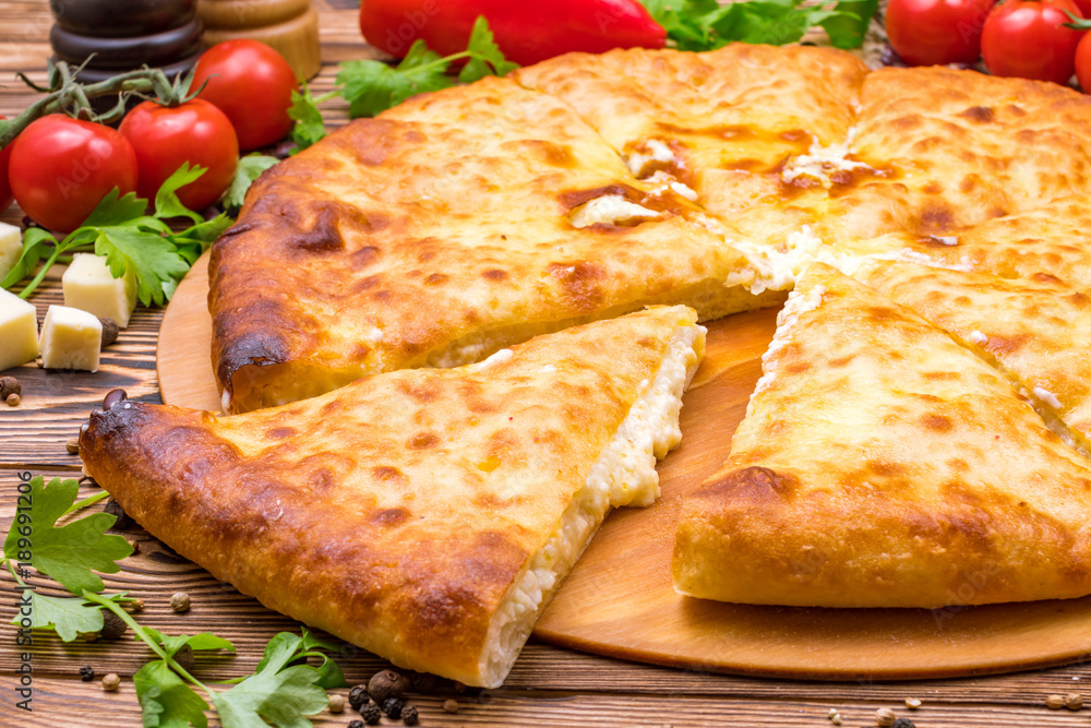 Ossetian cheese pie on a wooden background Ossetian cheese pie on a wooden background