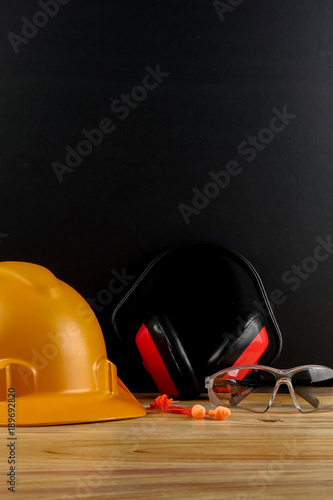 HEALTH AND SAFETY CONCEPT. Personal protective equipment on wooden table over black background.