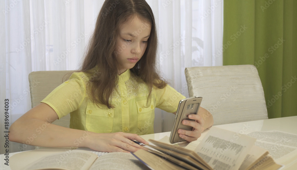 Teenager girl does homework with smartphone Teenager girl does homework with smartphone
